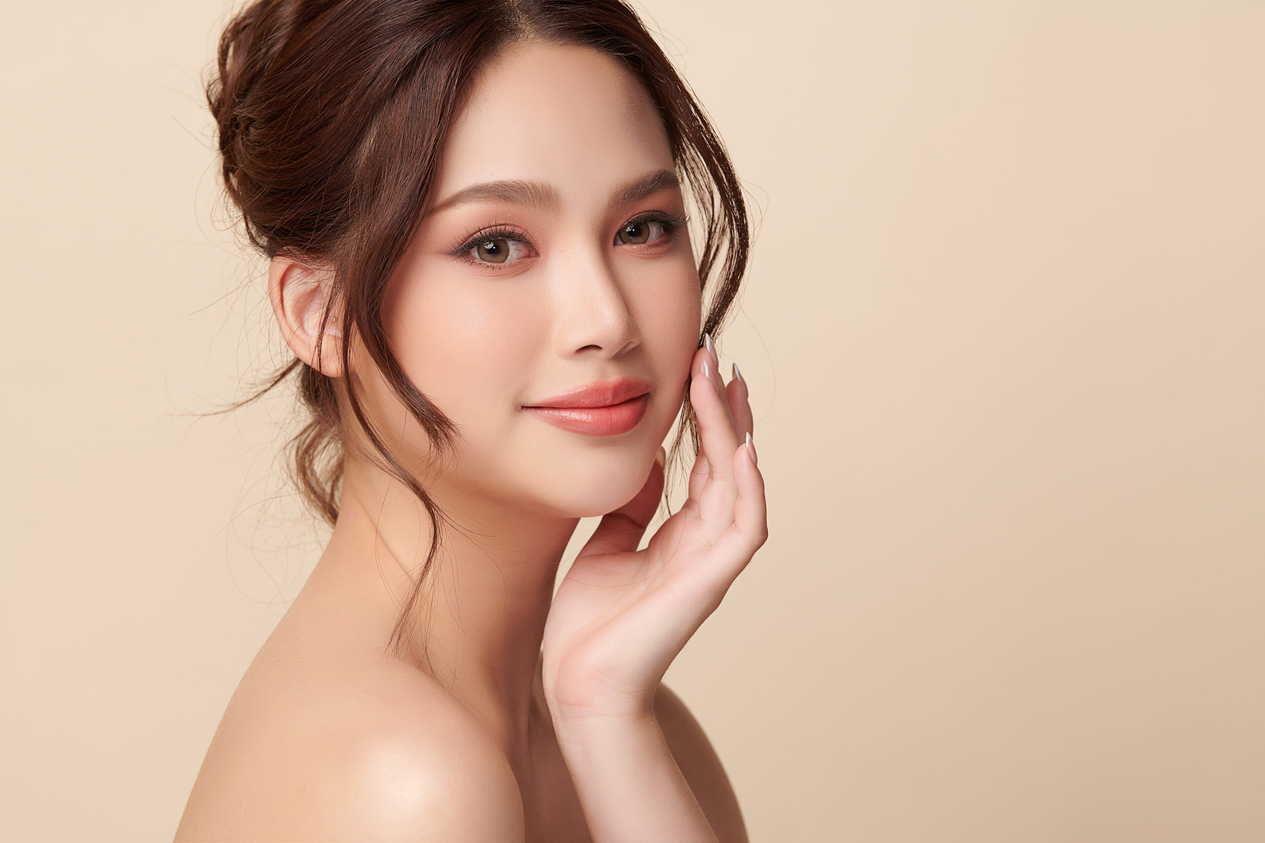A beautiful young Asian woman with clean, fresh skin against a beige background