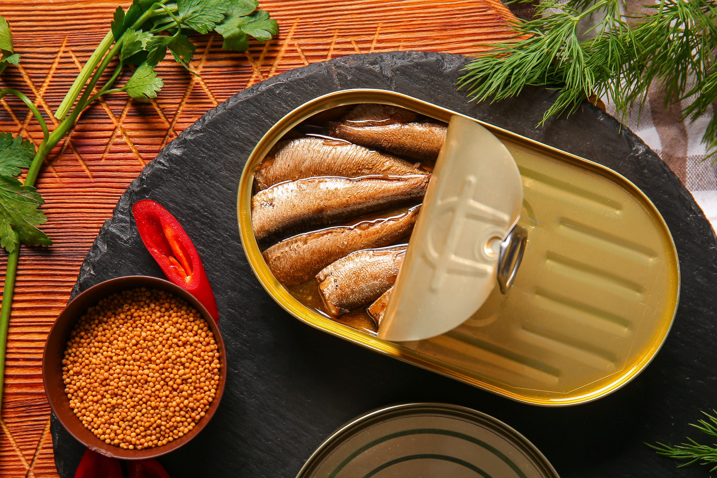 Canned smoked sprats with parsley and dill on table