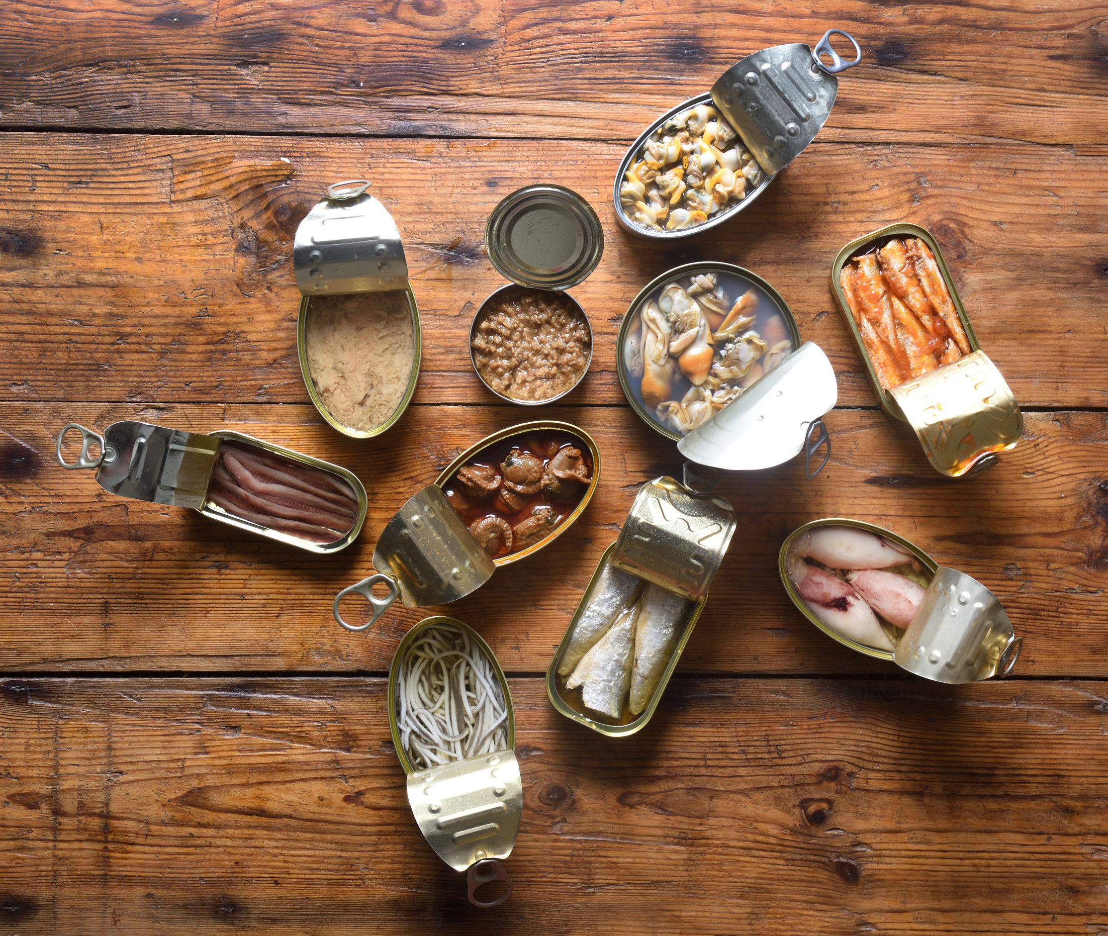 set of cans with fish and seafood on wooden background